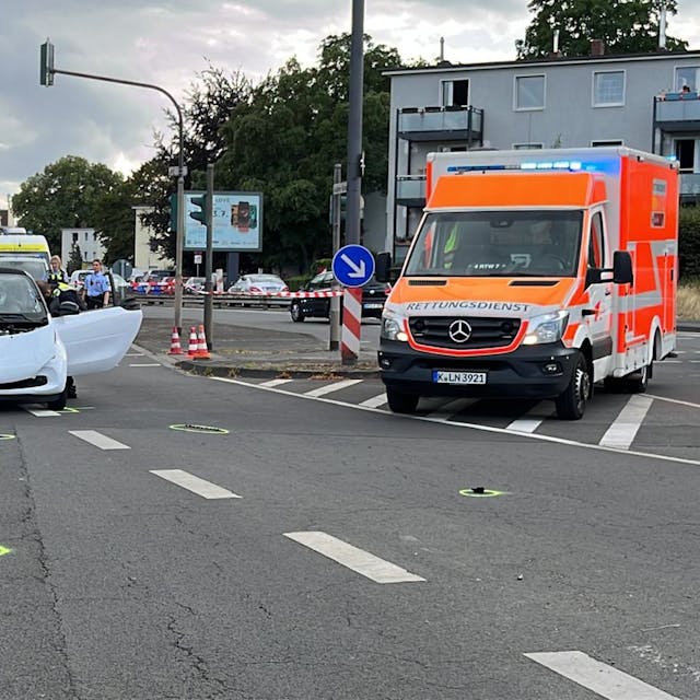 Unfallort mit einem demonlierten Auto, einem auf dem Boden liegenden Fahrrad und einem Krankenwagen
