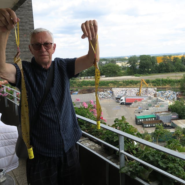 Peter Peterlini mit Fliegenfängern auf dem Balkon. Im Hintergrund das Presswerk.