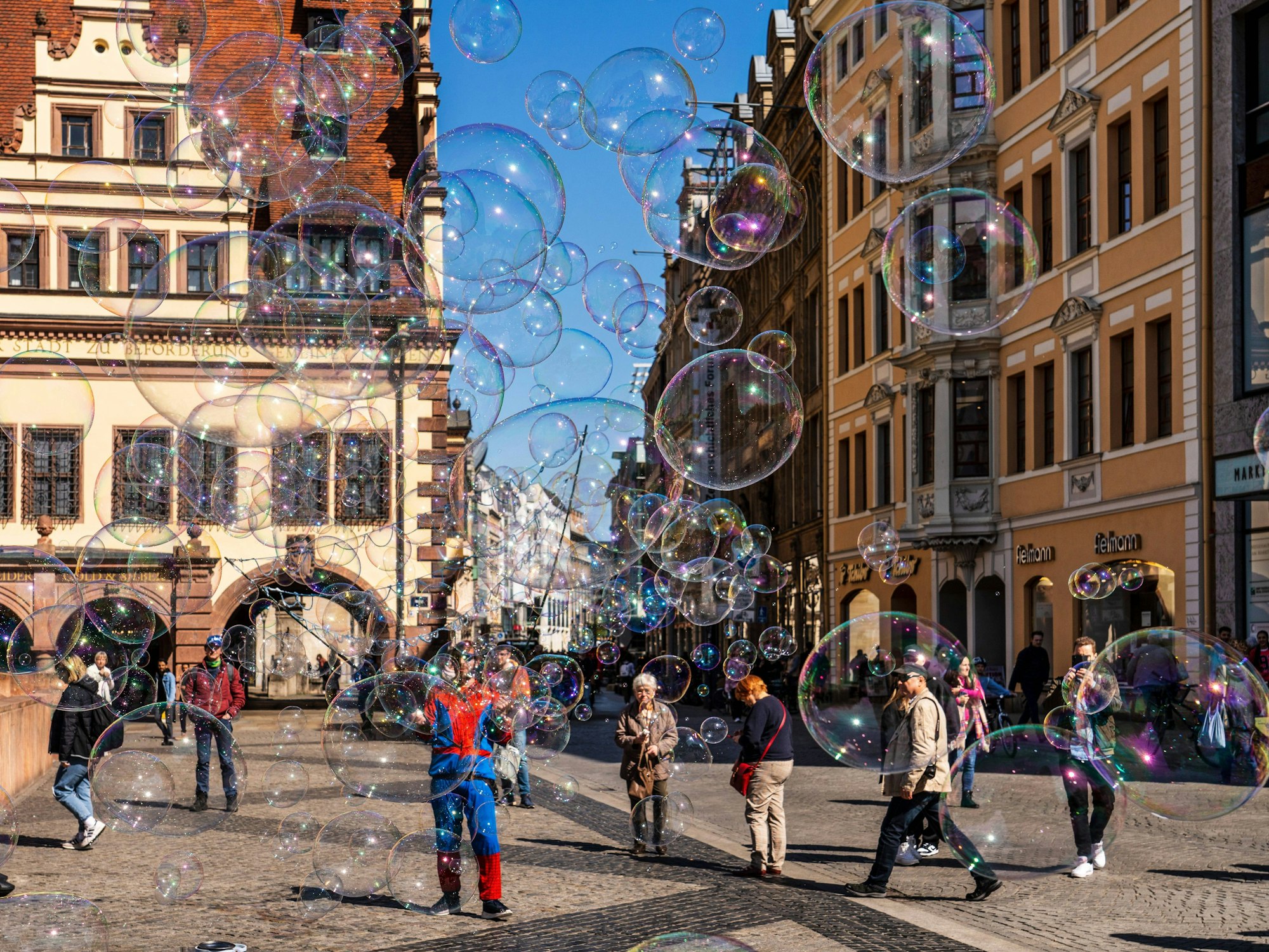 Seifenblasen eines Straßenkünstlers fliegen über den Marktplatz von Leipzig.