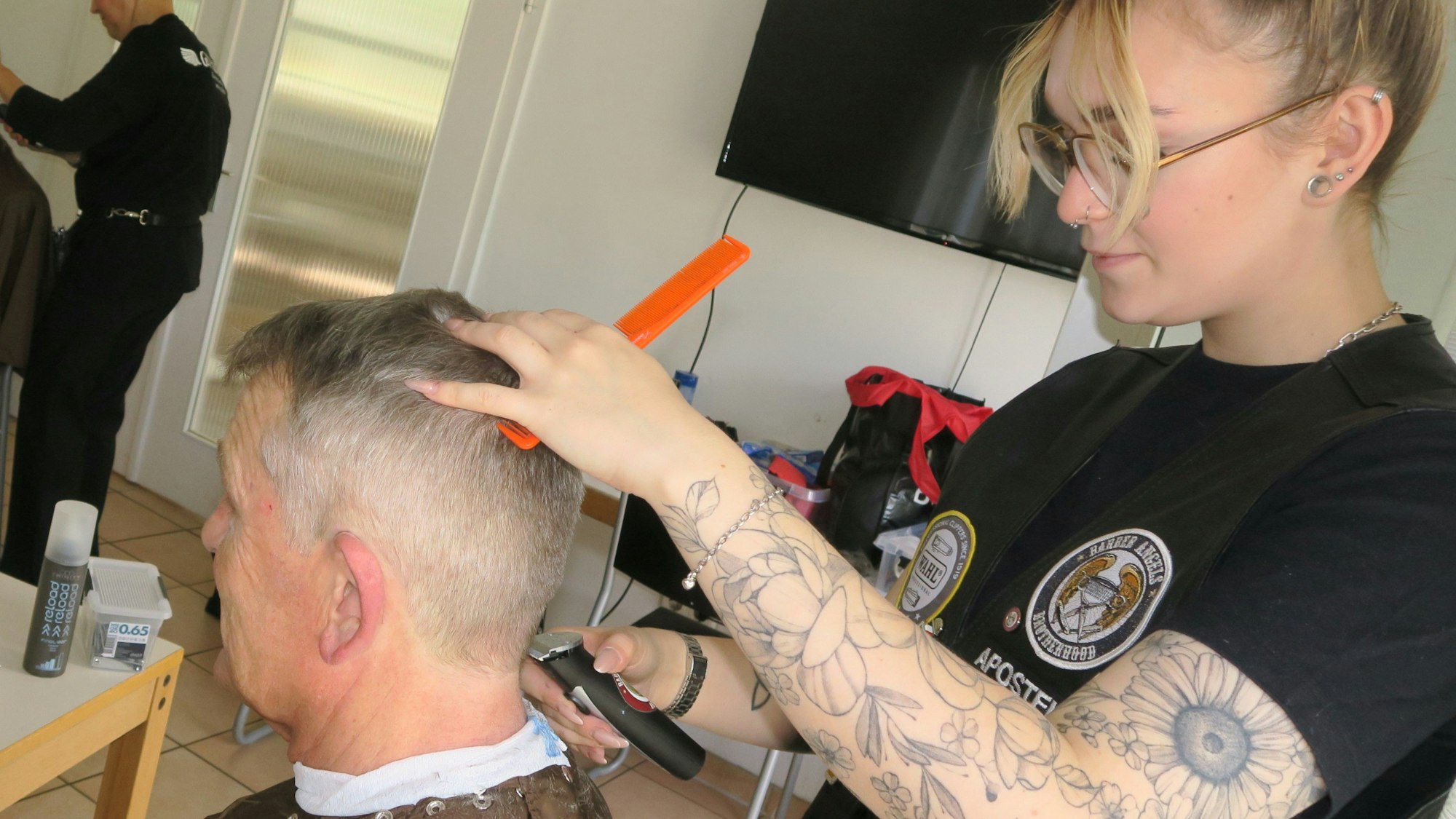 Freiseurin rasiert Mann die Haare.