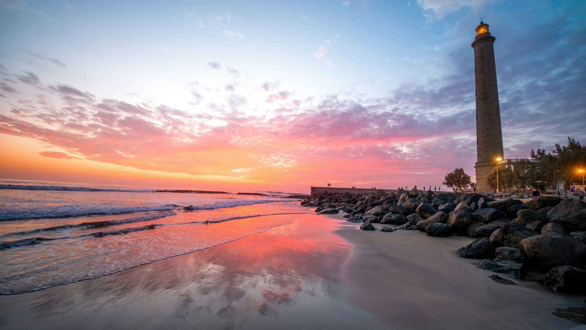 Auf dem Foto sieht man die Playa de Maspalomas samt Leuchtturm im Sonnenuntergang.