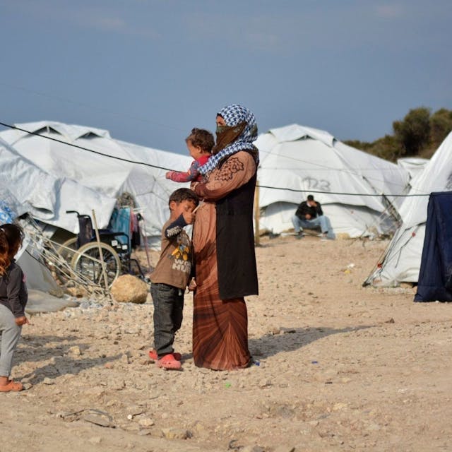 Eine Frau steht mit einem Baby im Arm und drei kleinen Kindern im Flüchtlingslager Kara Tepe in der Nähe von Mytilini auf Lesbos zwischen Zelten.