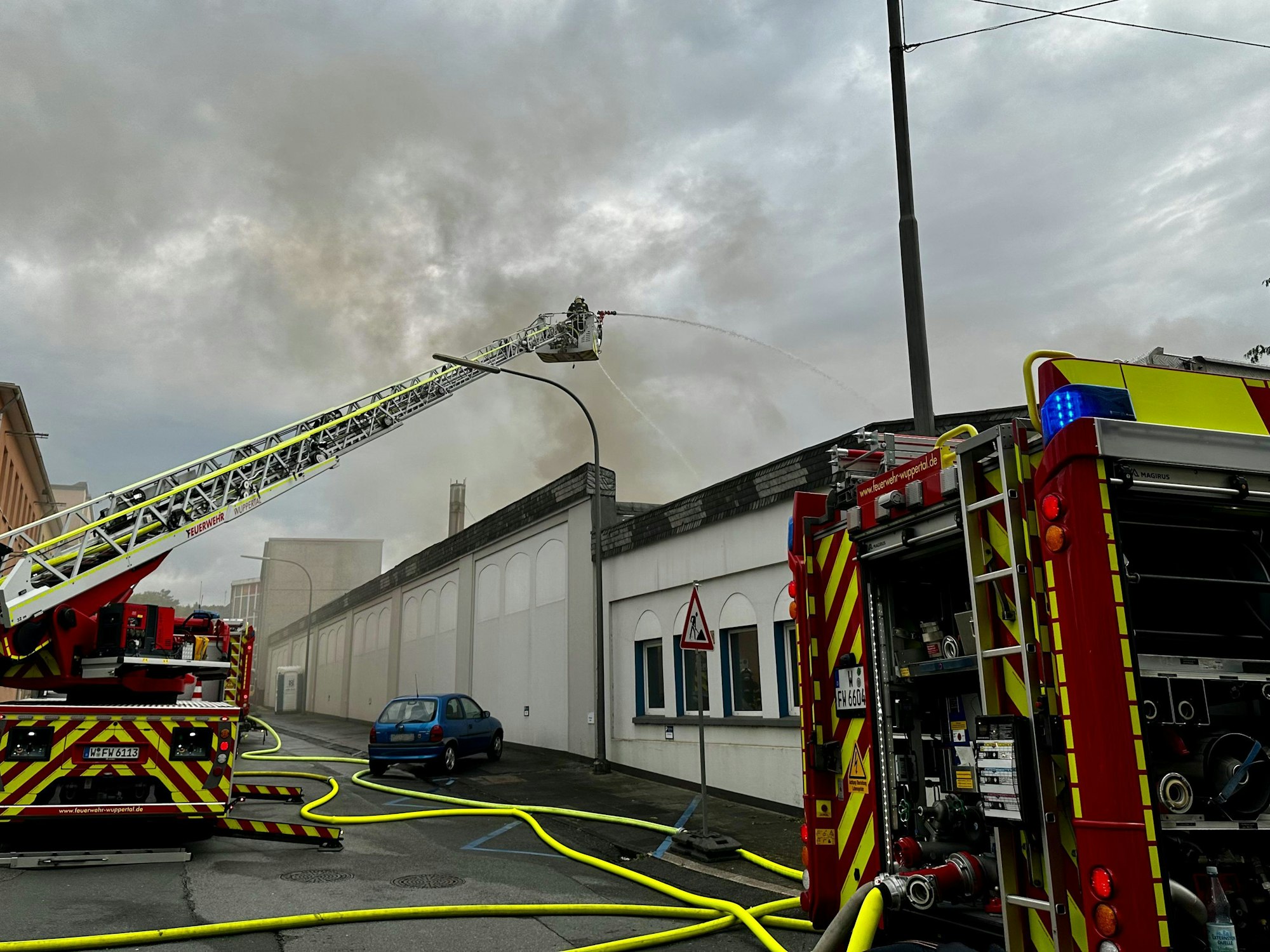 Feuerwehrleute bekämpfen einen Dachstuhlbrand in einem Gewerbebetrieb.