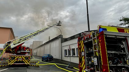 Feuerwehrleute bekämpfen einen Dachstuhlbrand in einem Gewerbebetrieb.