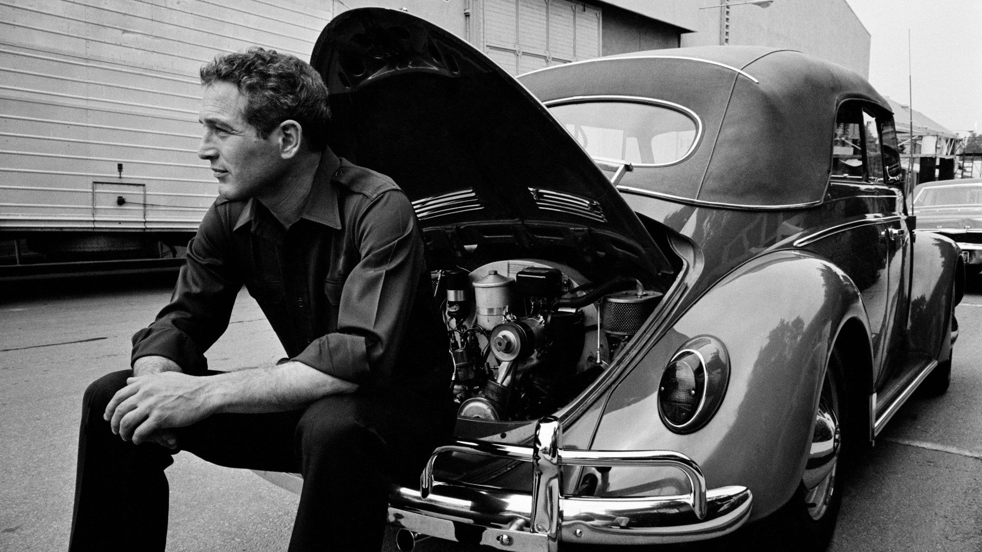 Das Foto aus dem Jahr 1967 zeigt den Schauspieler Paul Newman, der auf der Stoßstange eines VW Käfer sitzt.