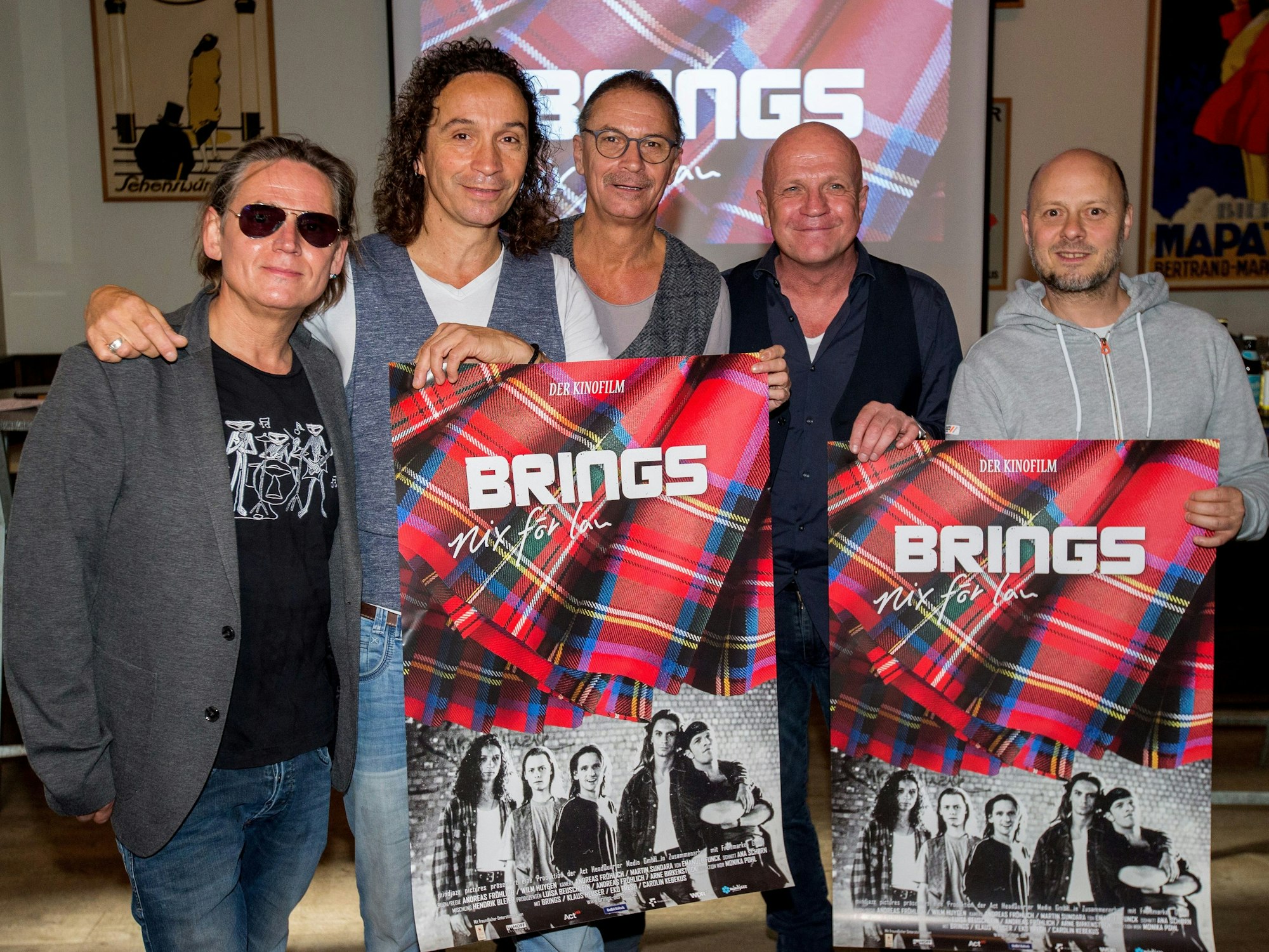 Harry Alfter, Stephan Brings, Peter Brings, Christian Blüm und Kai Engel posieren mit einem Filmplakat.