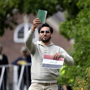 Ein Demonstrant hält eine Kopie des Korans gemeinsam mit einer irakischen Fahne vor der irakischen Botschaft in die Luft.