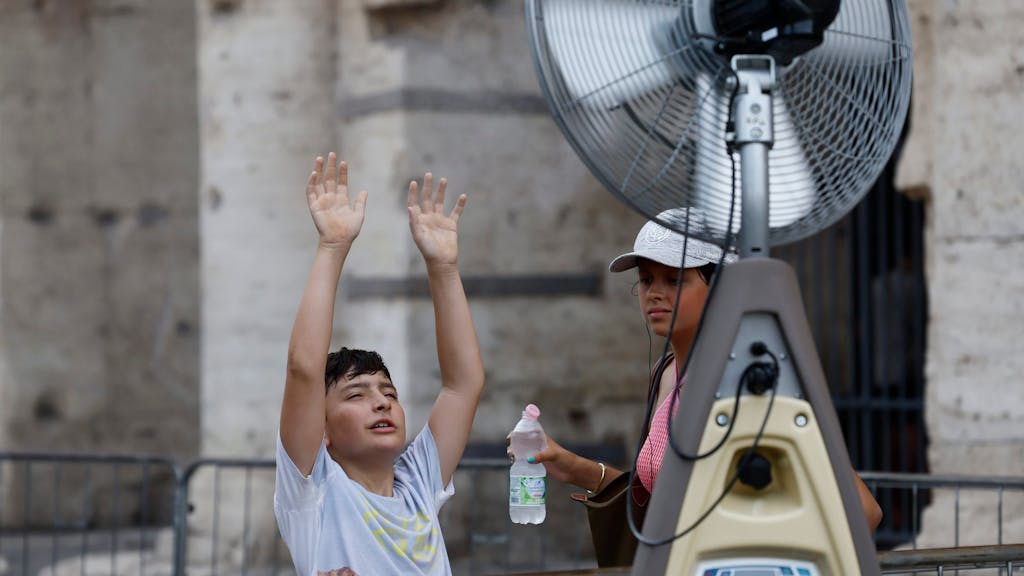 Ein Junge kühlt sich vor einem Ventilator in der Nähe des Kolosseums ab.