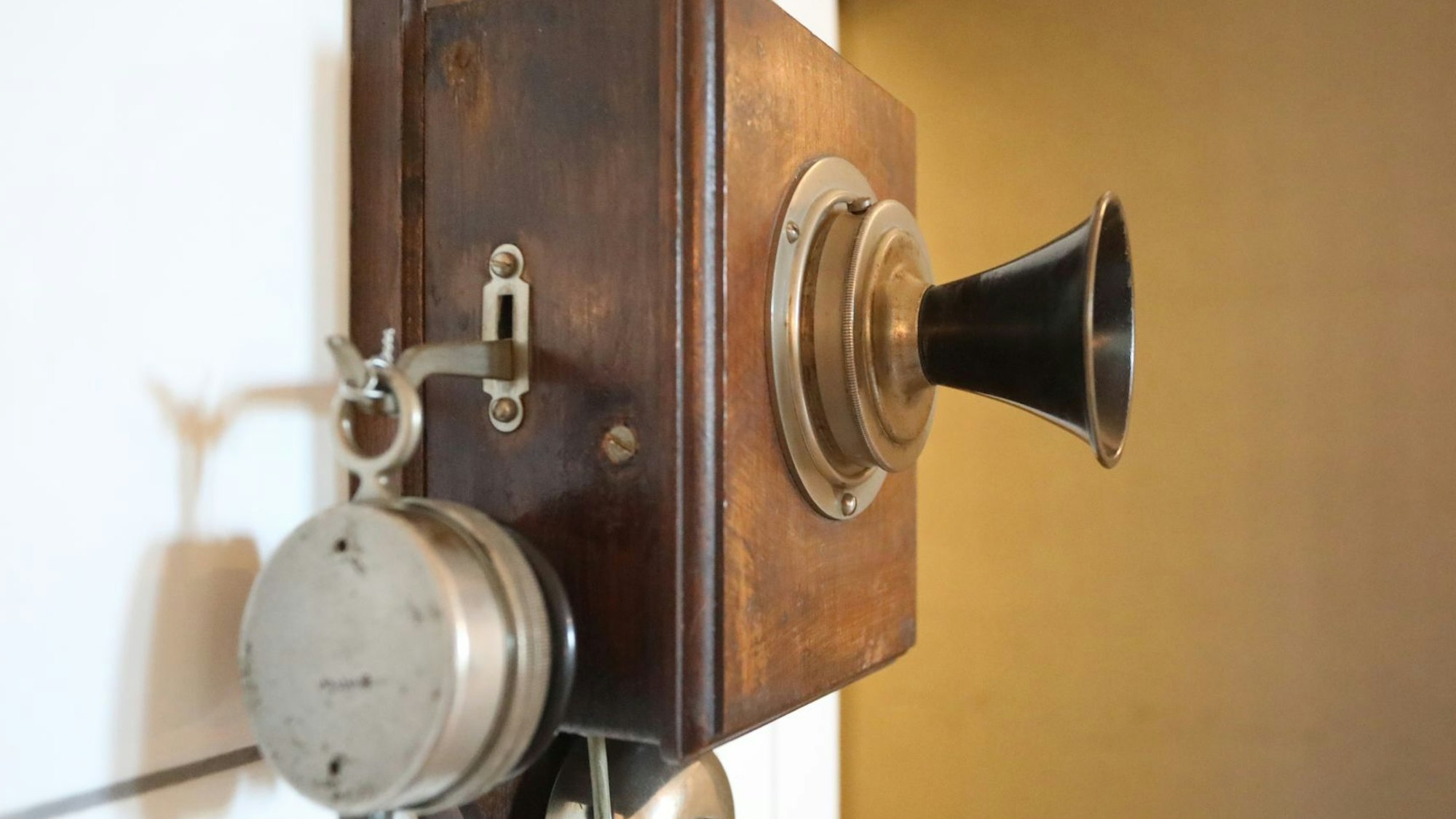 Ein altes Telefon aus Holz hängt an der Wand.