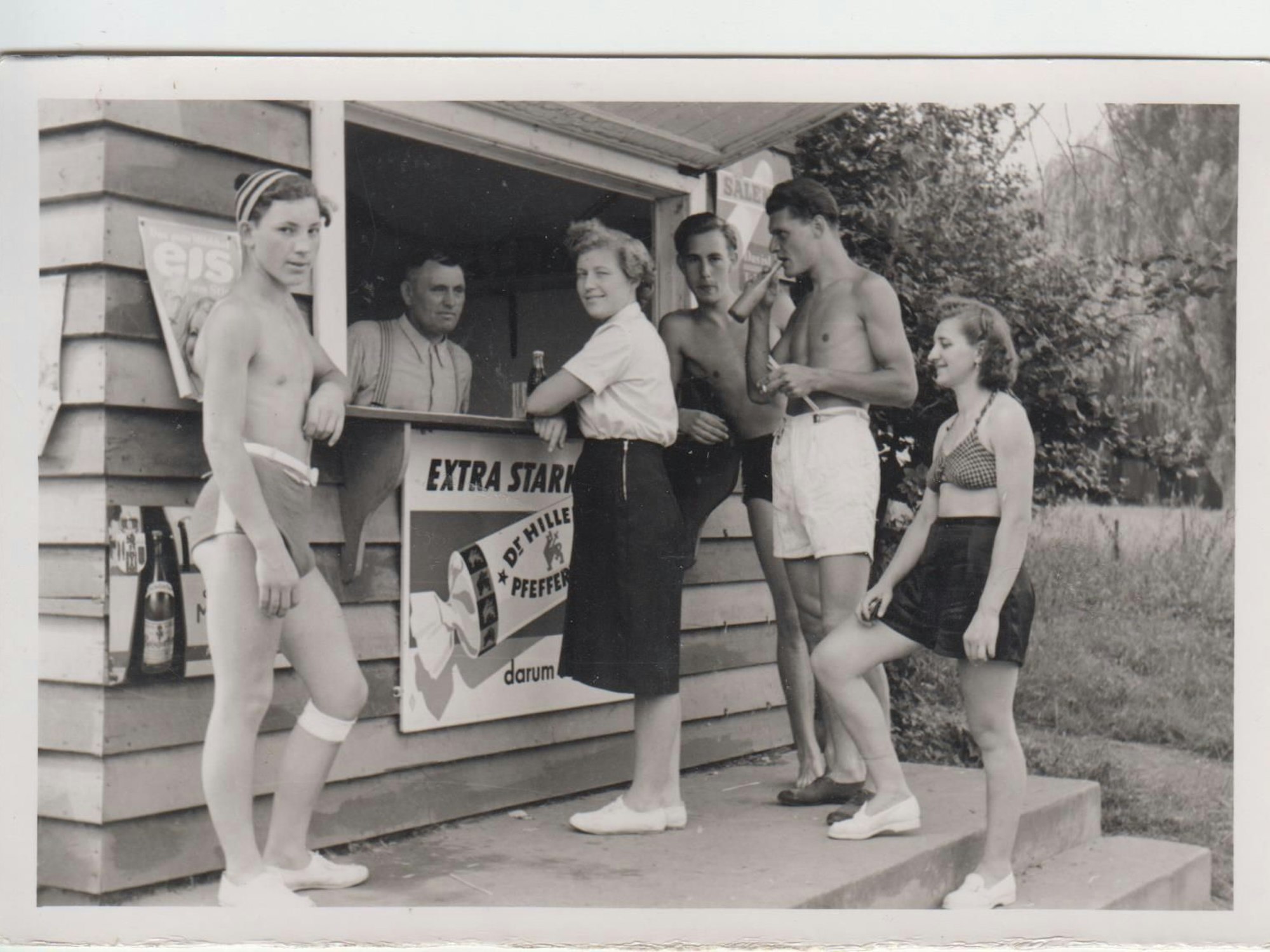 Ein historisches Foto zeigt Menschen in Badekleidung vor einem Trinkbüdchen um 1950.