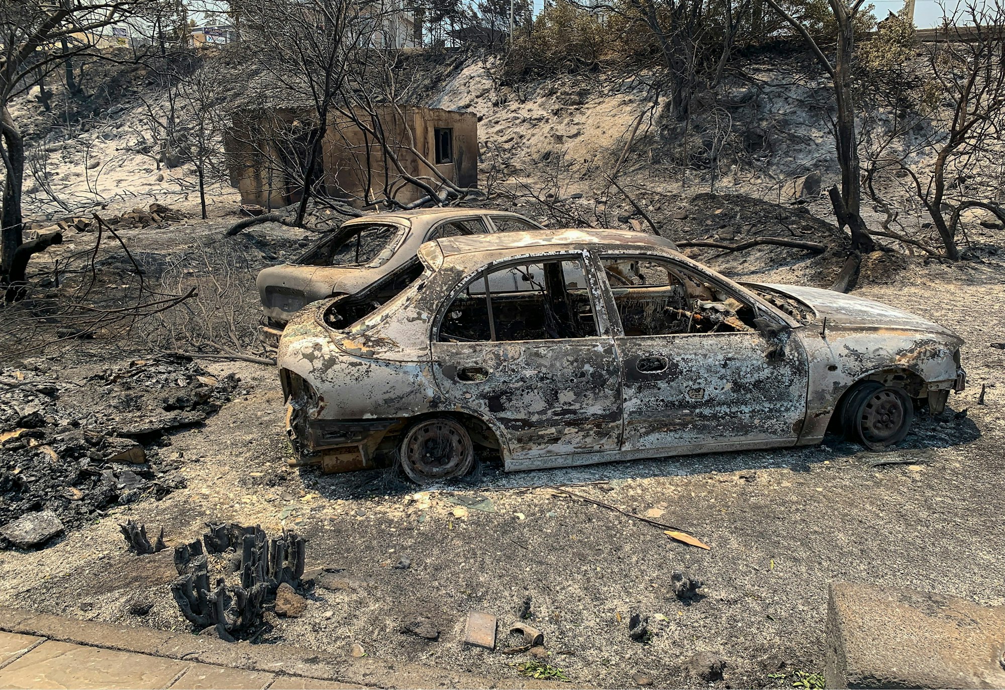 Griechenland, Rhodos: Verbrannte Autowracks stehen nach katastrophalen Waldbränden auf einer Straße.