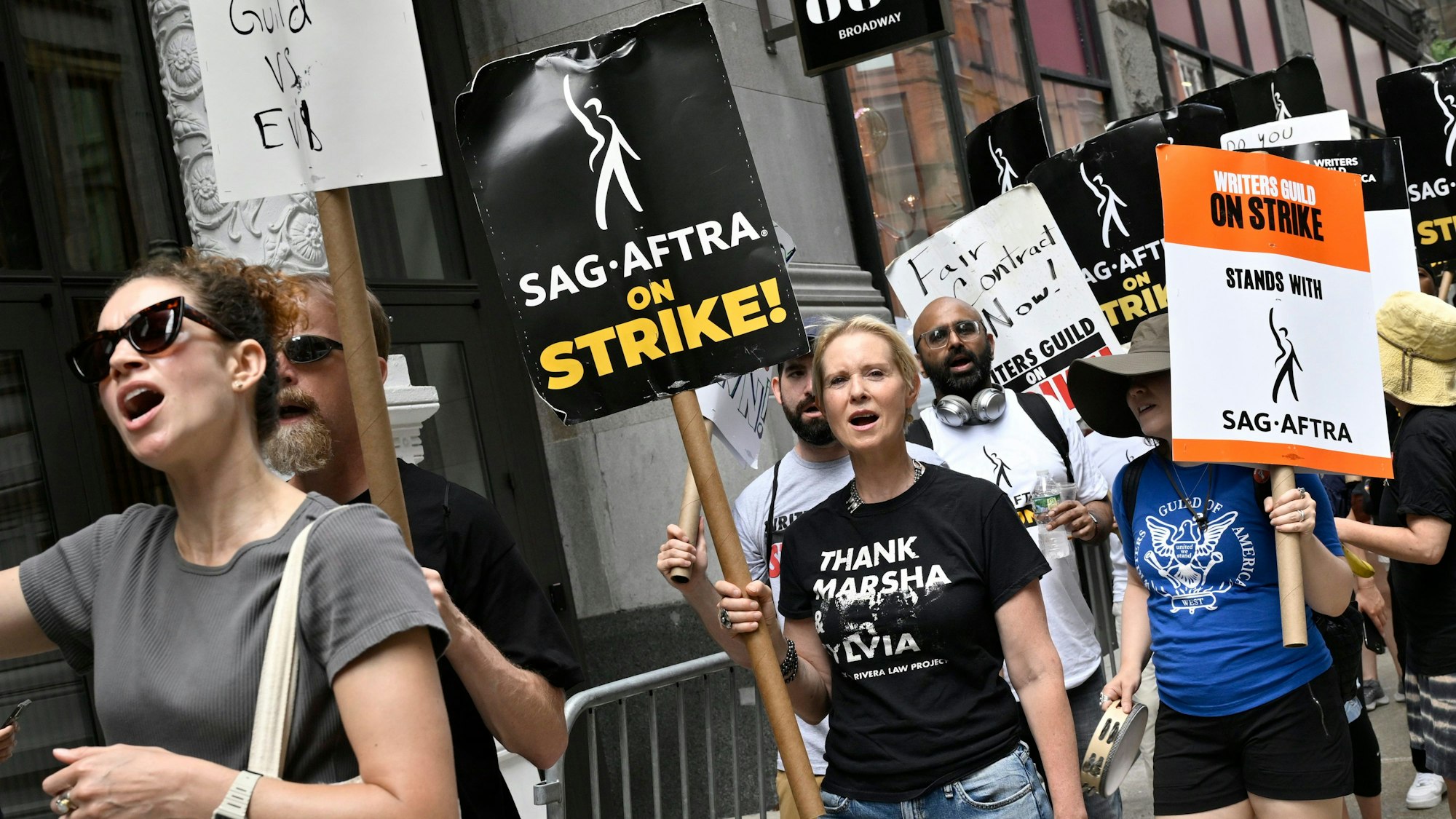 Cynthia Nixon (M), Schauspielerin aus den USA, trägt ein Schild während eines Streiks. Nach mehr als 60 Jahren streiken die Schauspieler und Drehbuchautoren in den USA erstmals wieder gemeinsam und dürften den Betrieb in der Filmindustrie auf unbestimmte Zeit lahmlegen.