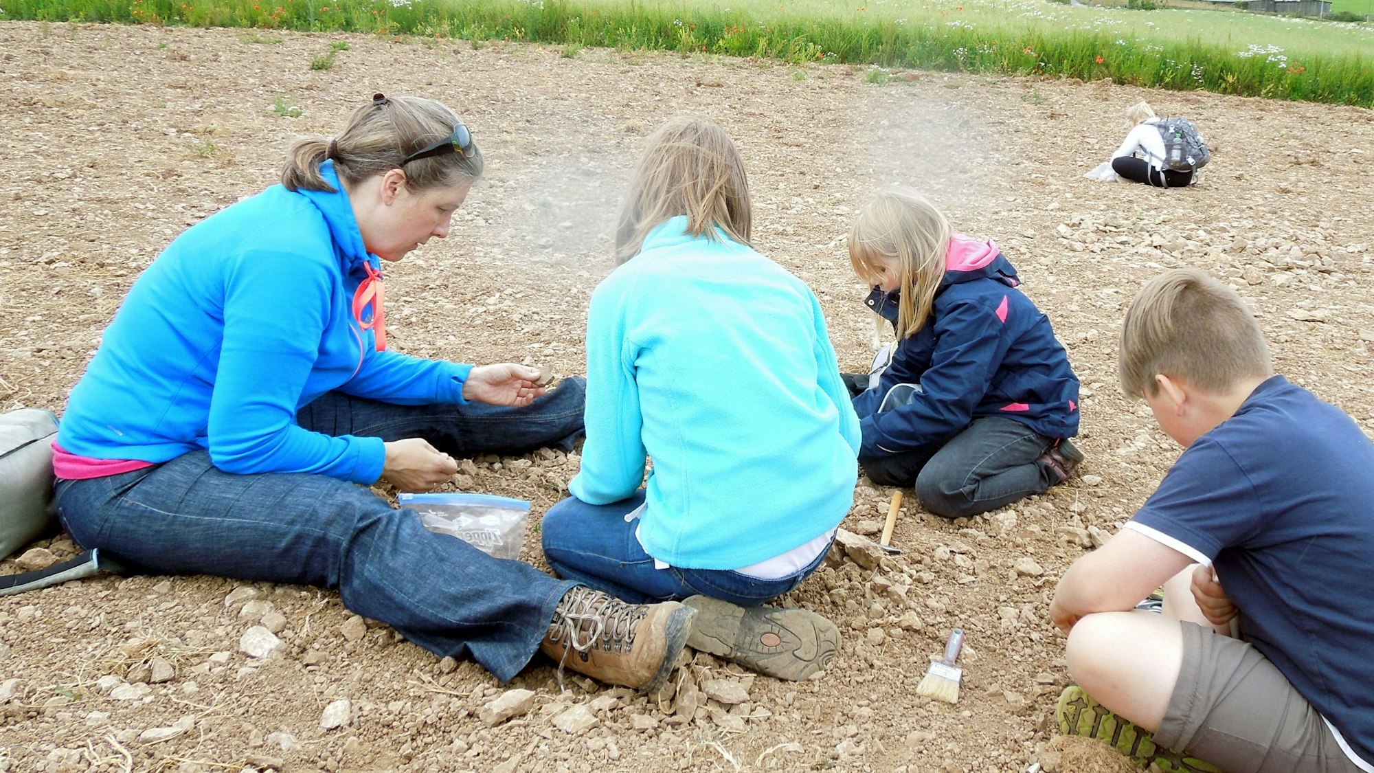 Eine Erwachsene und einige Kinder auf dem Fossilienacker in Nettersheim