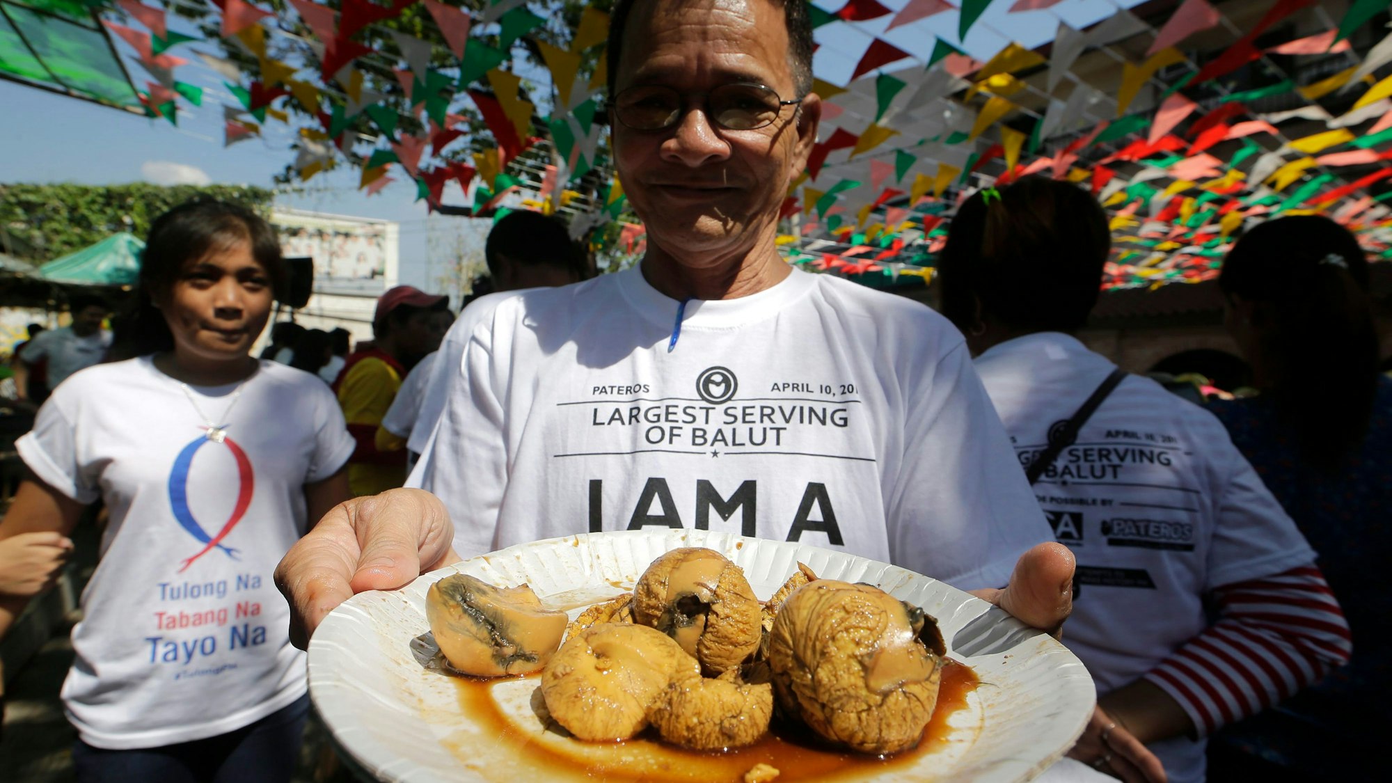 Ein Filipino zeigt einen Teller mit Balut.