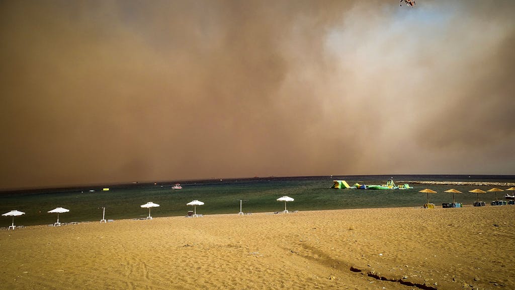 Ein Löschhubschrauber fliegt über einen Strand, während ein Waldbrand auf der griechischen Insel Rhodos wütet.&nbsp;