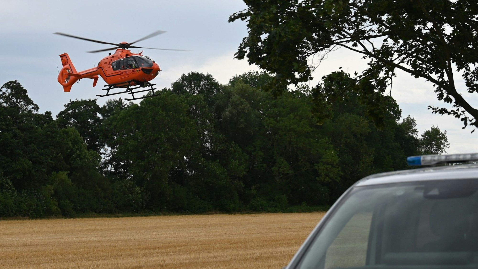 Das Bild zeigt einen Hubschrauber vor einem Polizeifahrzeug.