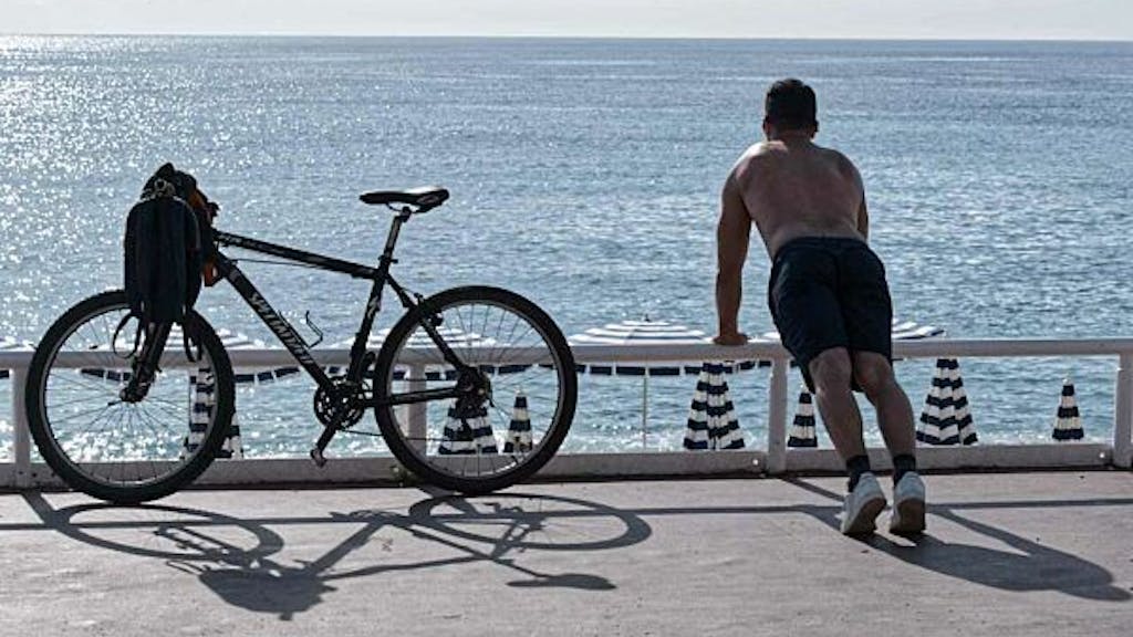 Mann und Fahrrad auf einer Promenade mit Blick aufs Meer.