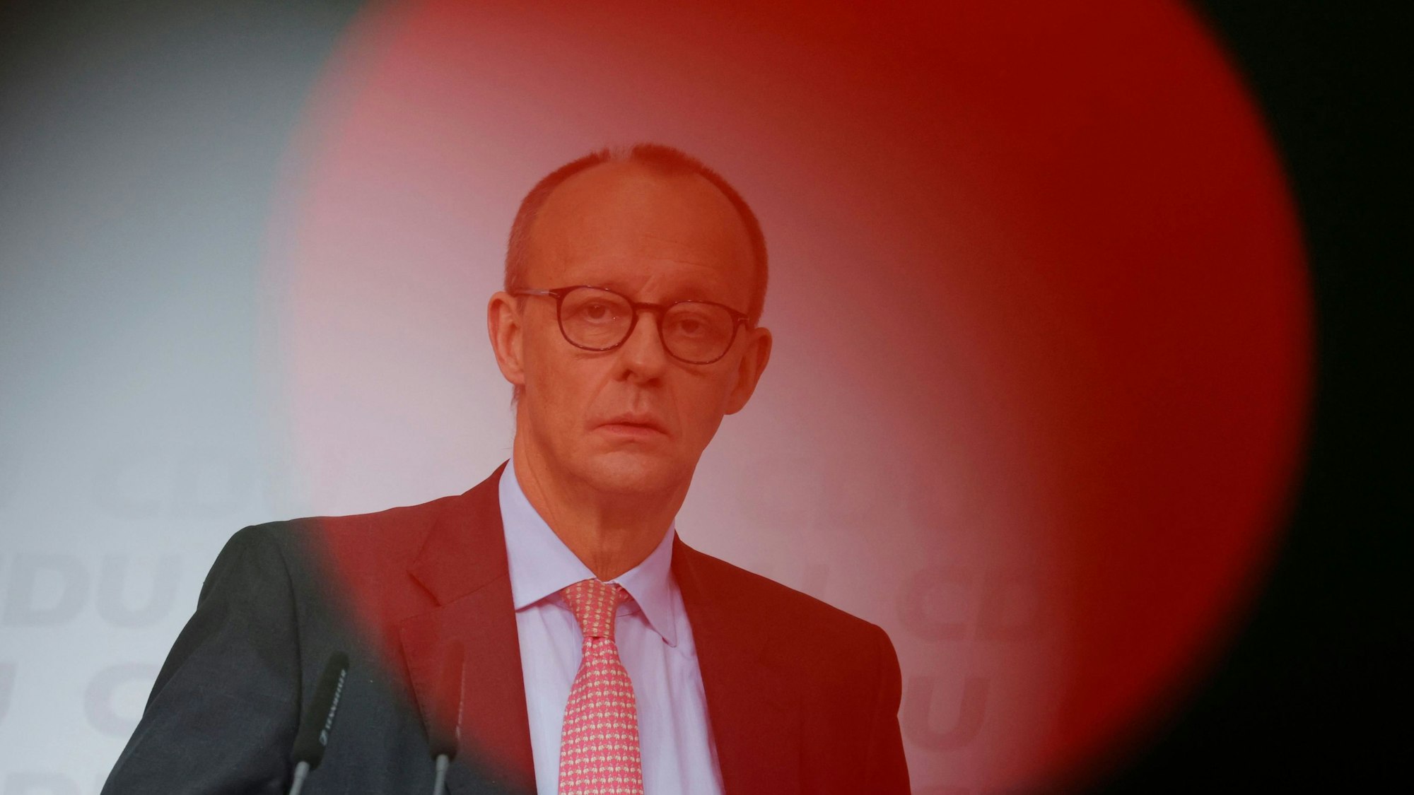 Der CDU-Vorsitzende Friedrich Merz in einem blassroten Lichtkegel