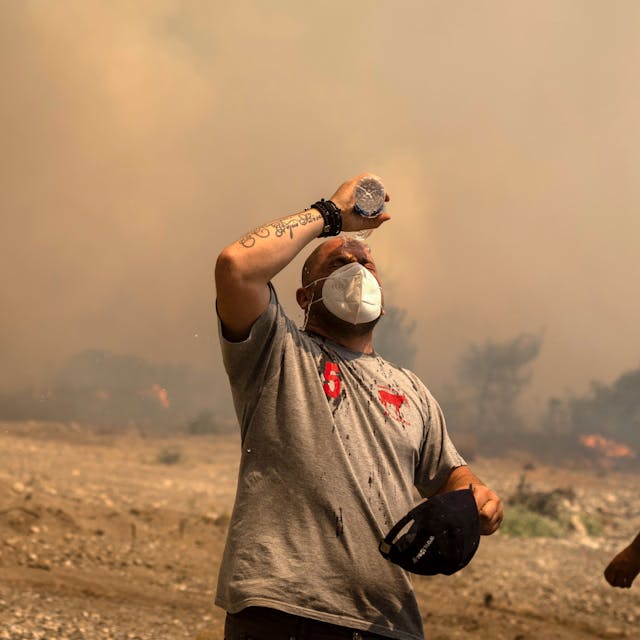 25.07.2023, Griechenland, Rhodos: Ein Freiwilliger Helfer kühlt sich während eines Waldbrandes in der Ortschaft Vati ab. Starke Winde erschweren den Kampf gegen die Waldbrände auf der griechischen Ferieninsel Rhodos. Foto: Petros Giannakouris/AP/dpa +++ dpa-Bildfunk +++