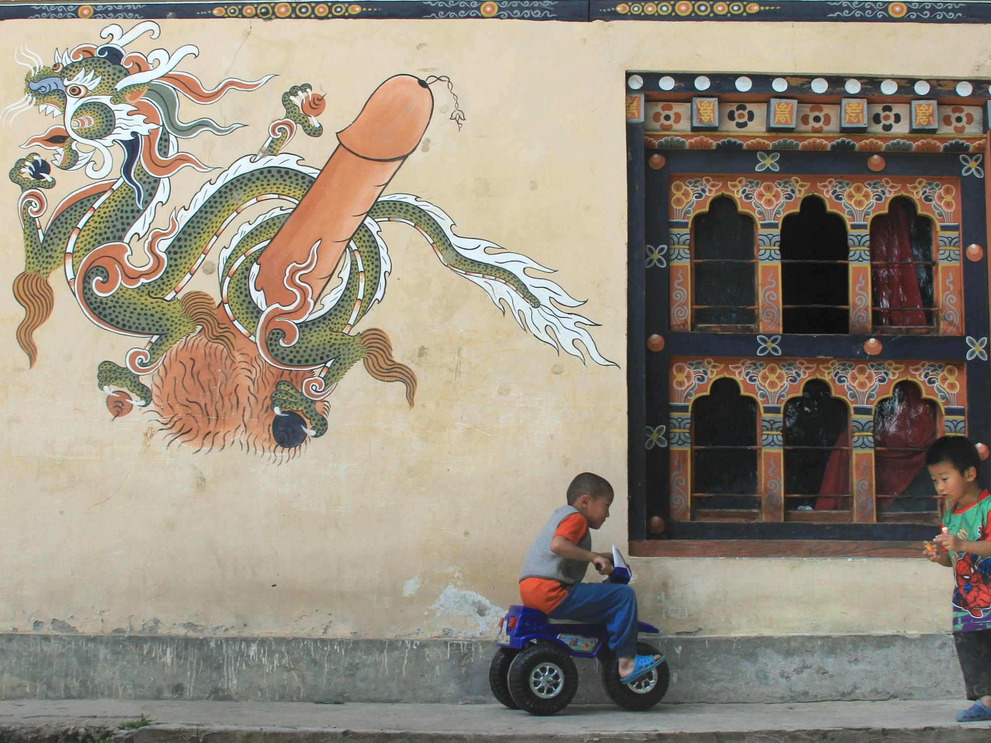 Kinder 2013 vor einer Penis-Malerei in Thimphu in Bhutan.