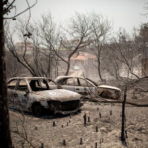 Verbrannte Autos stehen nach einem Waldbrand im Dorf Kiotari. Auf Rhodos und in anderen Teilen Griechenlands toben als Folge einer enormen Hitzewelle Waldbrände.