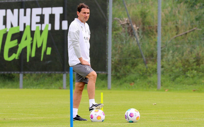 Der neue, starke Mann auf der Position des Cheftrainers bei Fußball-Bundesligist Borussia Mönchengladbach: Gerardo Seoane. Hier zu sehen am 24. Juli 2023 während des Trainingslagers am Tegernsee. Seoane hat seinen rechten Fuß auf einen Ball gestellt und schaut auf das Geschehen.