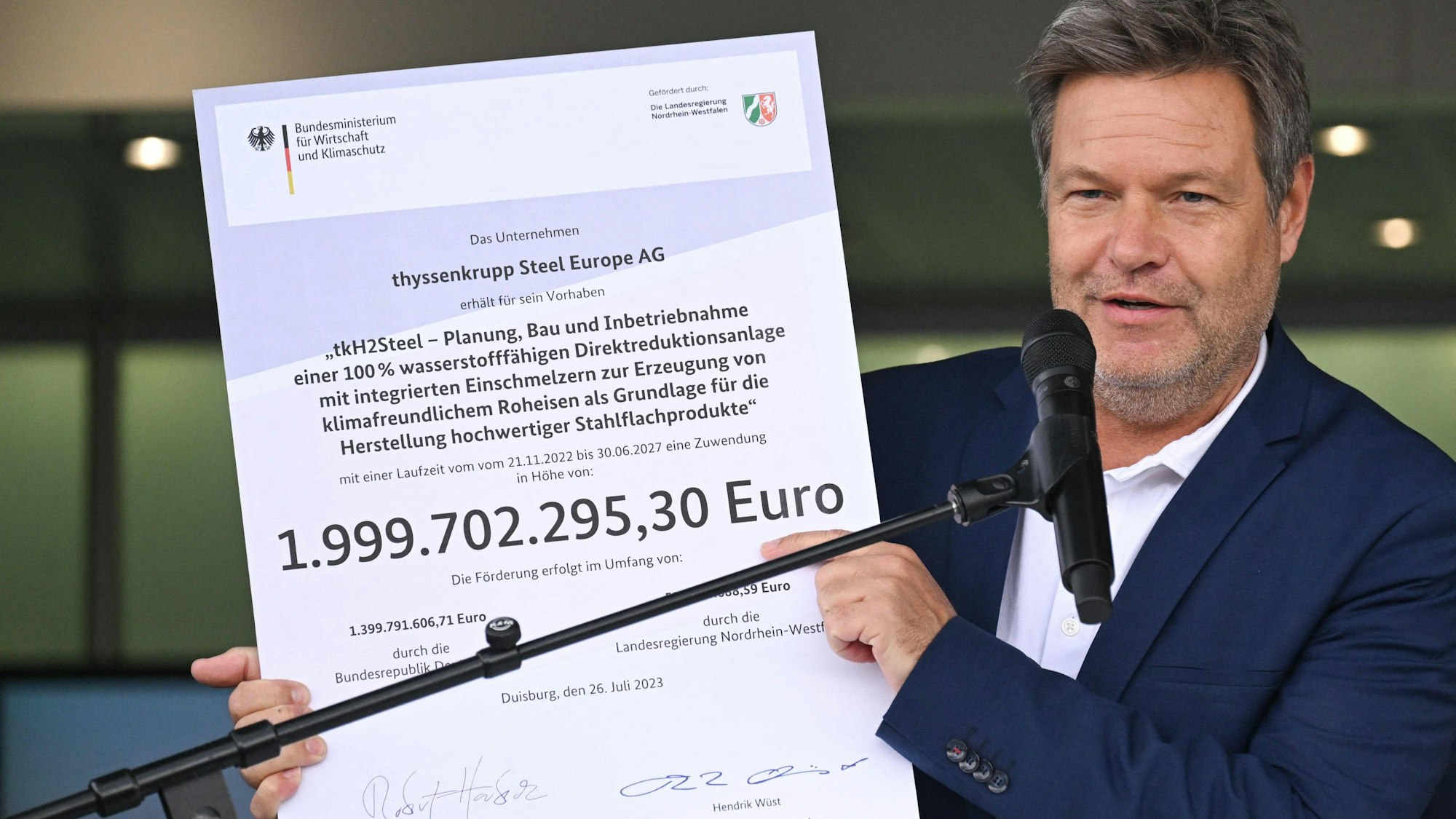 Robert Habeck zeigt den Förderbescheid über knapp zwei Milliarden Euro.