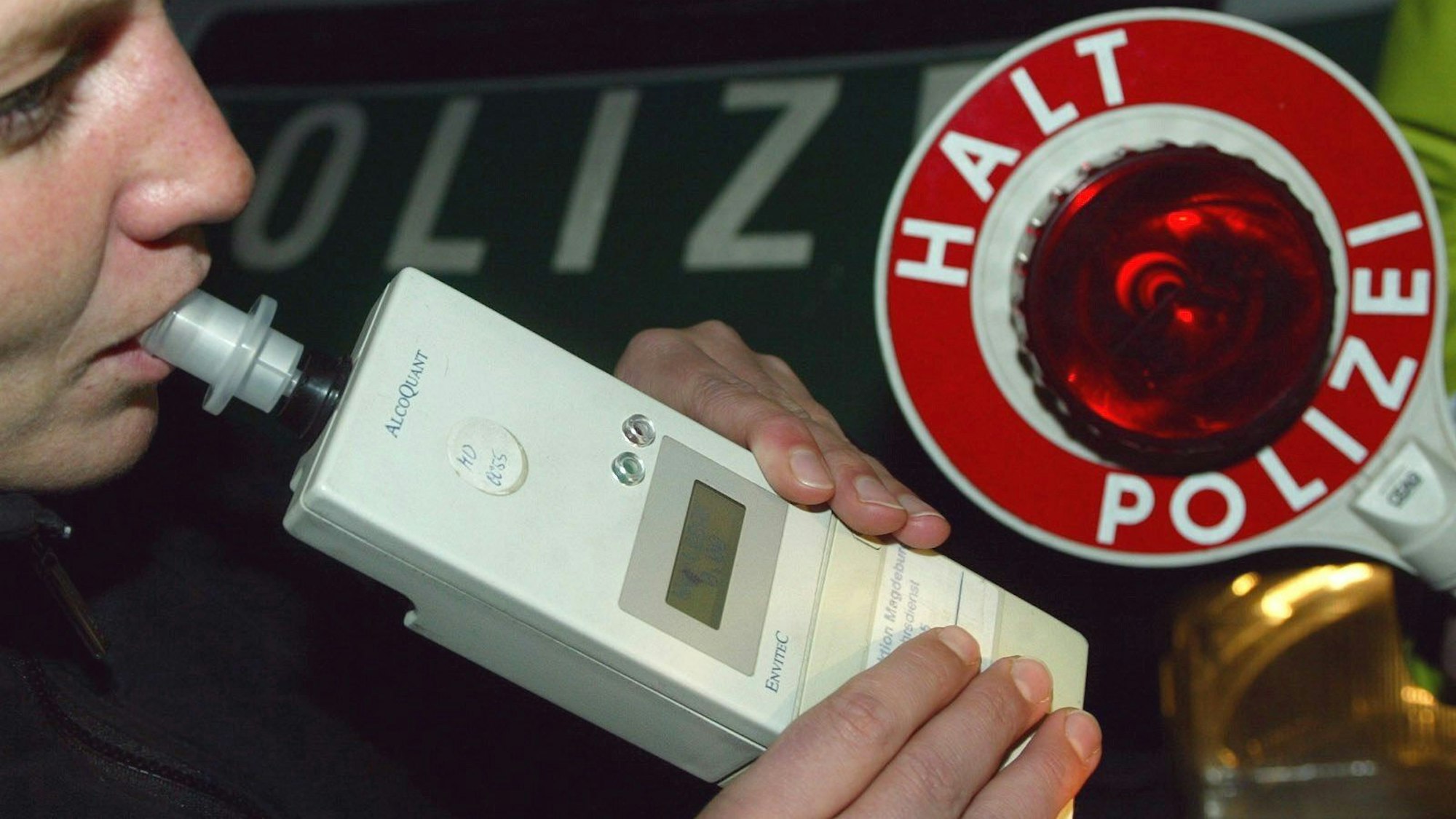 Eine Autofahrerin pustet einer Verkehrskontrolle der Polizei in ein Alkohol-Atemmessgeraet.