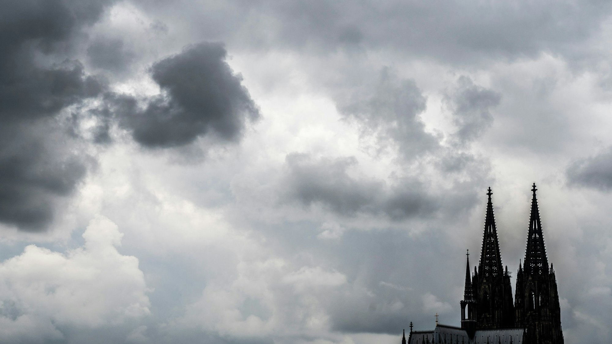 Eine leitende Mitarbeiterin des Erzbistums Köln hat ein wegweisendes Urteil gegen ihren Arbeitgeber erstritten. Unser Bild zeigt den Dom vor dunklen Wolken.