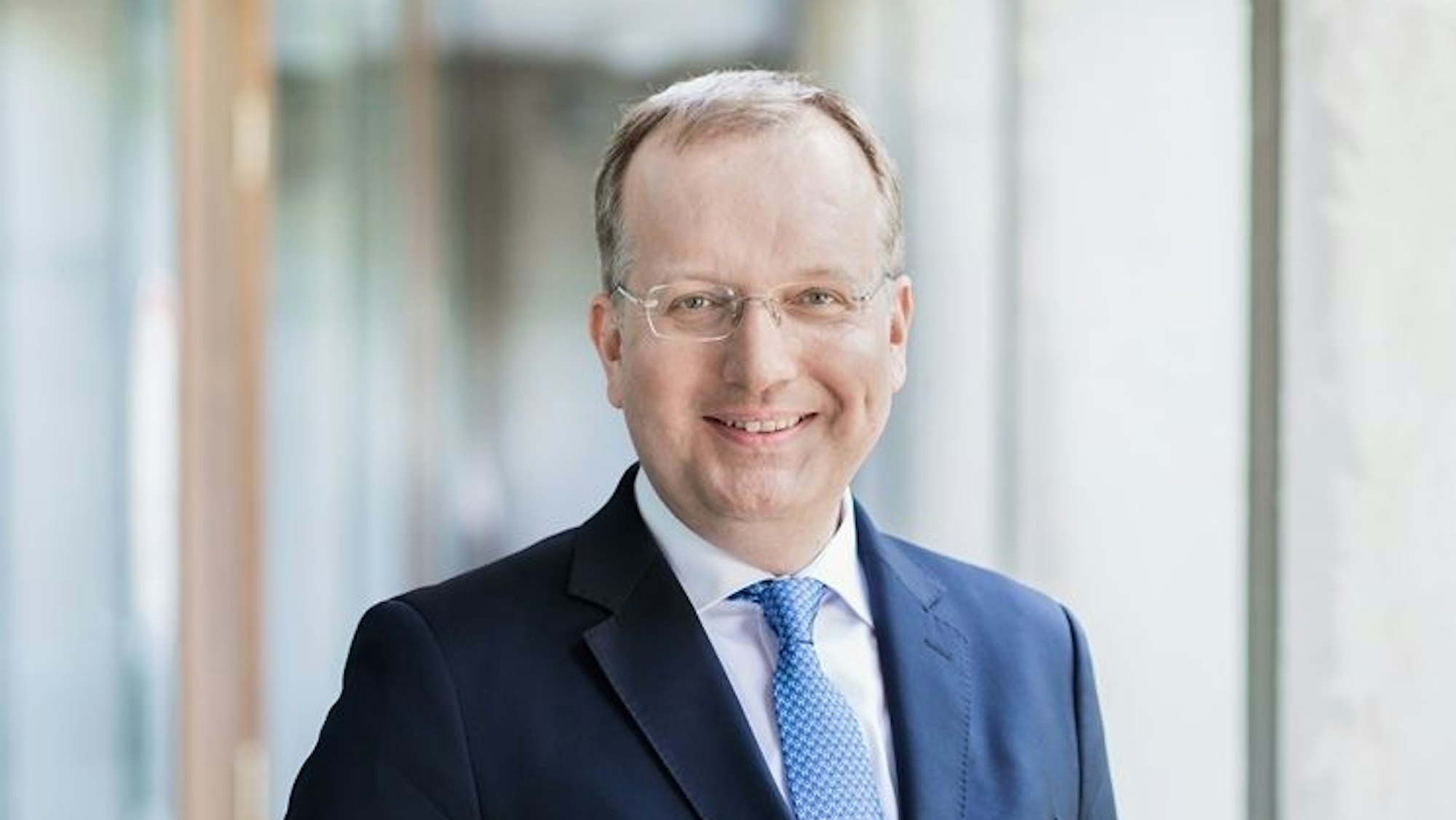 Ein Porträtfoto von Markus Ogorek. Der Rechtswissenschaftler trägt einen blauen Anzug, eine blaue Krawatte und eine Brille.