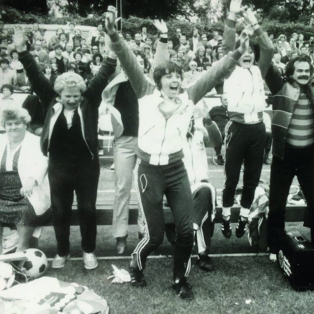 Spielerinnen und Trainer springen jubelnd am Spielfeldrand von einer Bank auf.