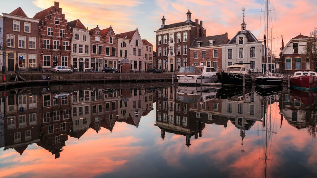 Boote liegen im kleinen Hafen der Stadt Goes in Zeeland. Über dem Ort geht die Sonne unter.