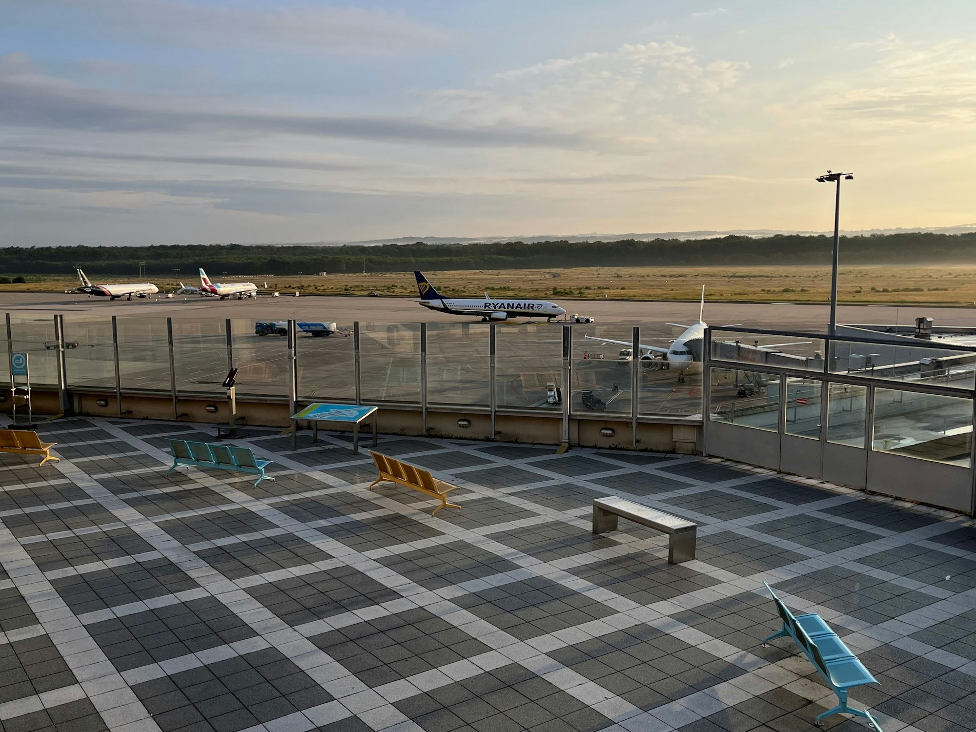 Von der Terrasse blickt man auf eine Start- und Landebahn und mehrere Flieger, die am Boden stehen.