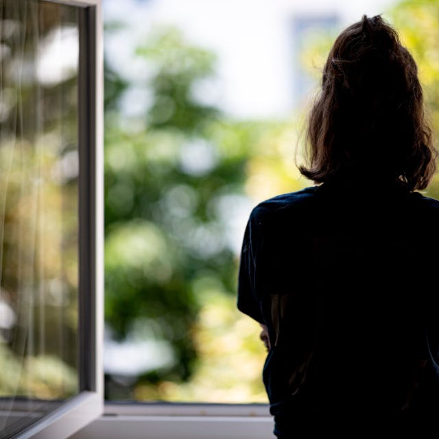 Berlin: Eine Frau steht in ihrer Wohnung an einem Fenster.&nbsp;