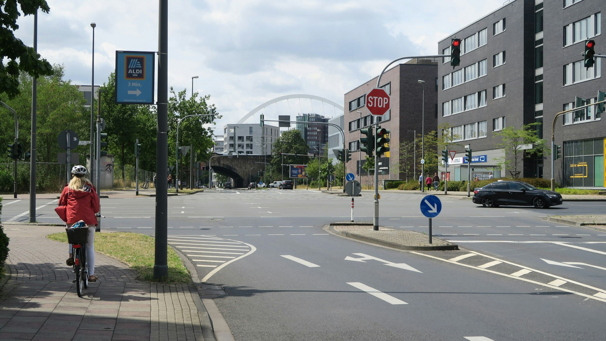 Blick über den Walter-Pauli-Ring auf die vierspurige Gummersbacher Straße mit der Lanxess-Arena im Hintergrund.