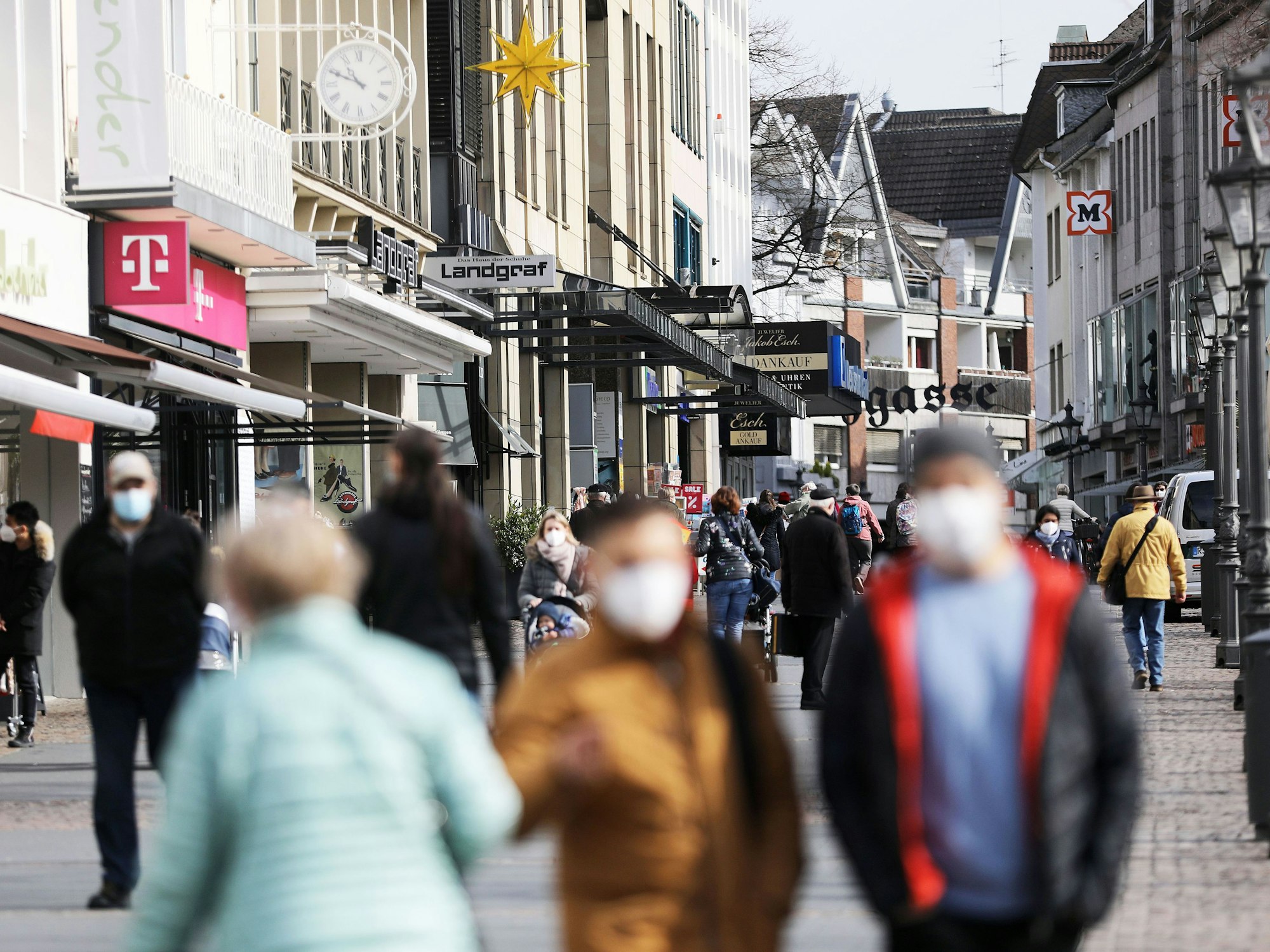 Menschen gehen mit Masken durch die Innenstadt von Siegburg.