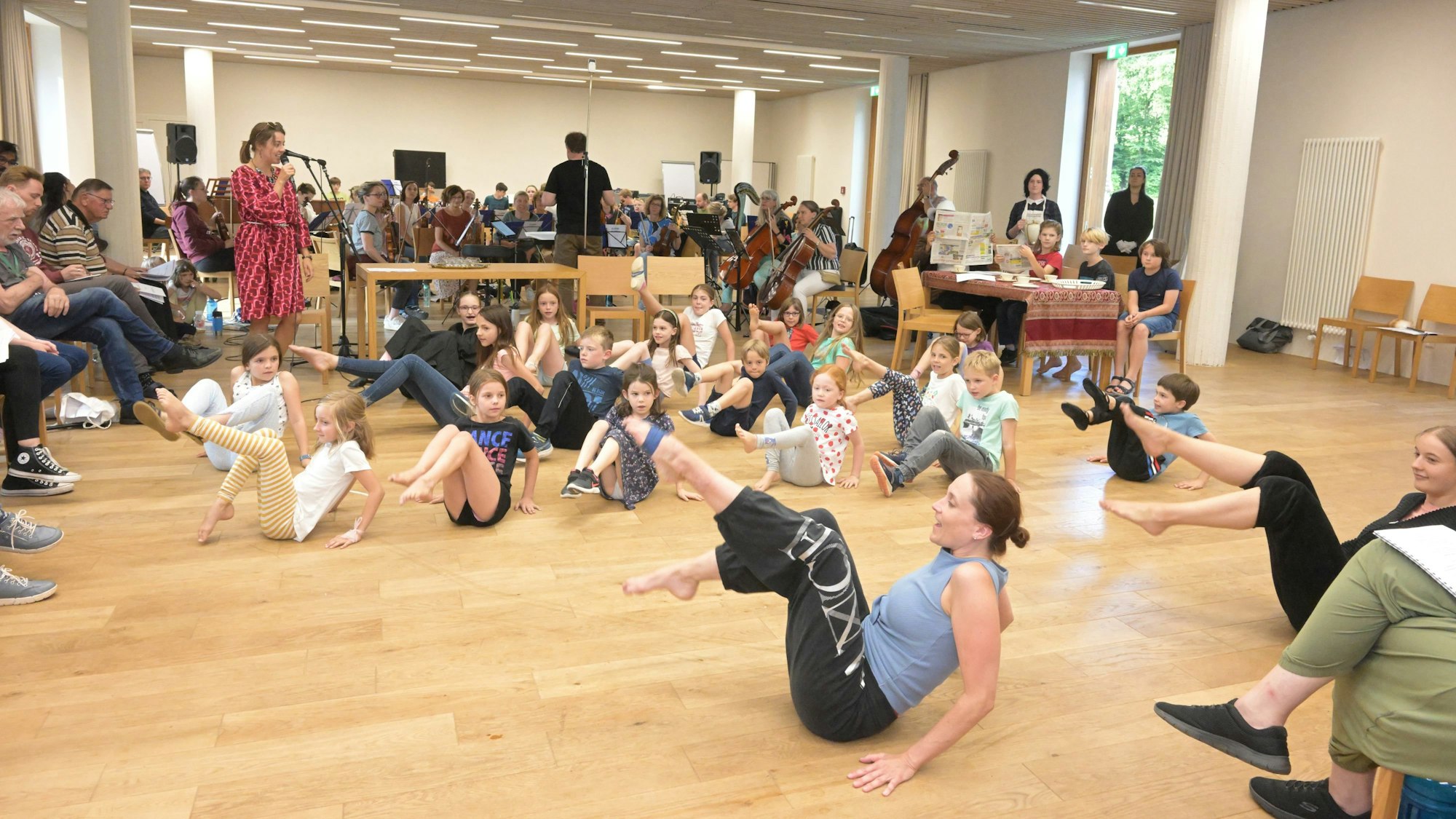 Kinder der Tanzgruppe sitzen auf dem Boden und üben einen Move.