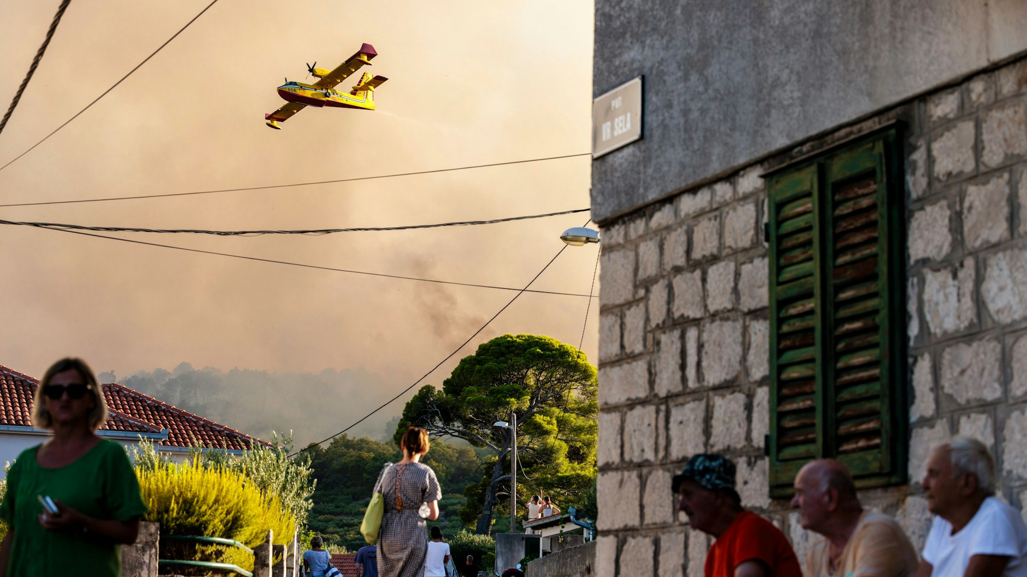 Ein Löschflugzeug versprüht Wasser, um einen Waldbrand auf der Insel Ciovo zu löschen.