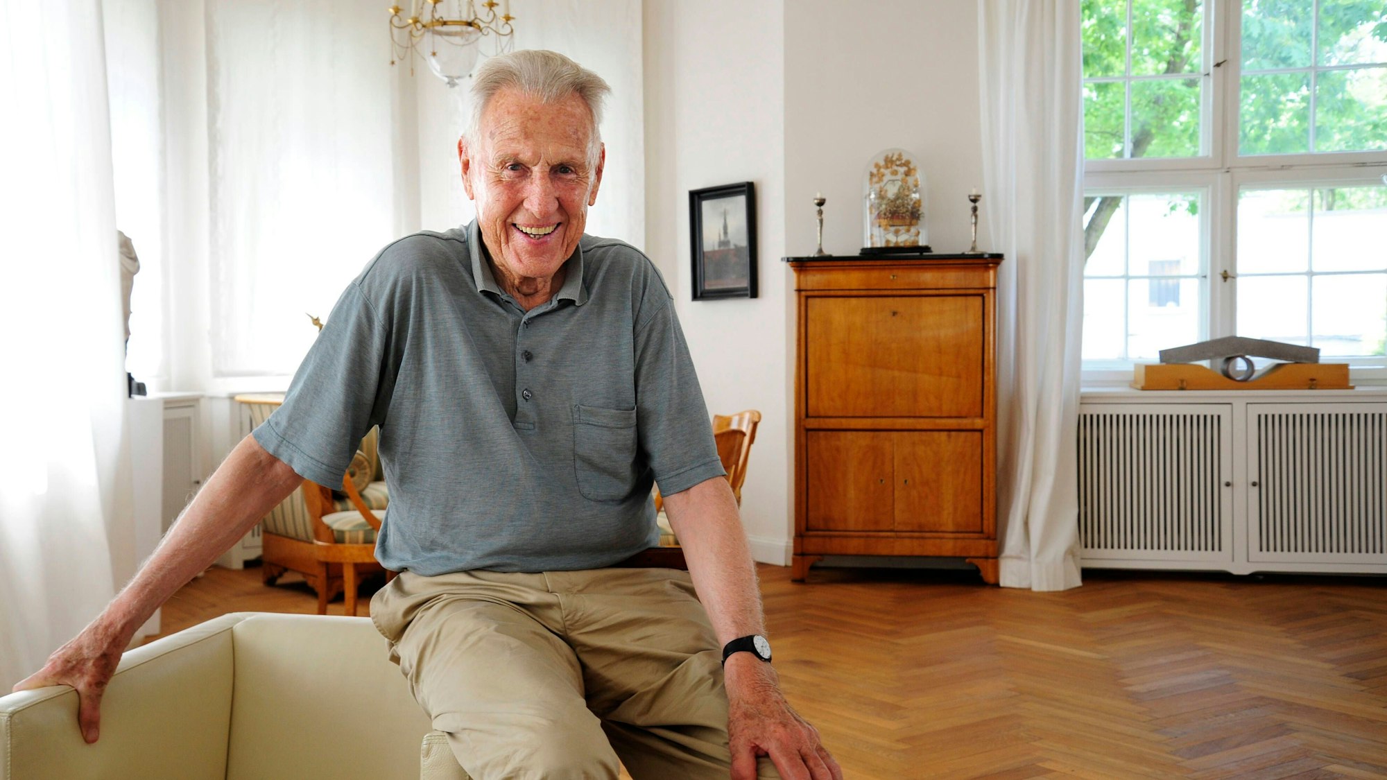 Der Kunsthändler Rudolf Zwirner sitzt auf einer Sessellehne in seinem Berliner Haus.