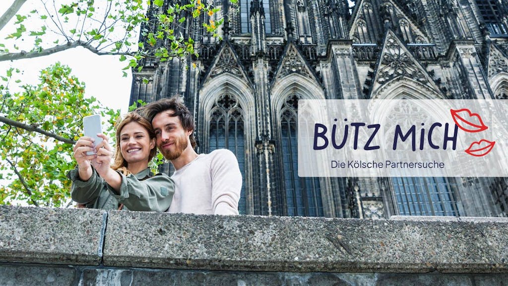 Mann und Frau schießen Selfie vorm Kölner Dom. Daneben das Logo der Website Bütz mich.