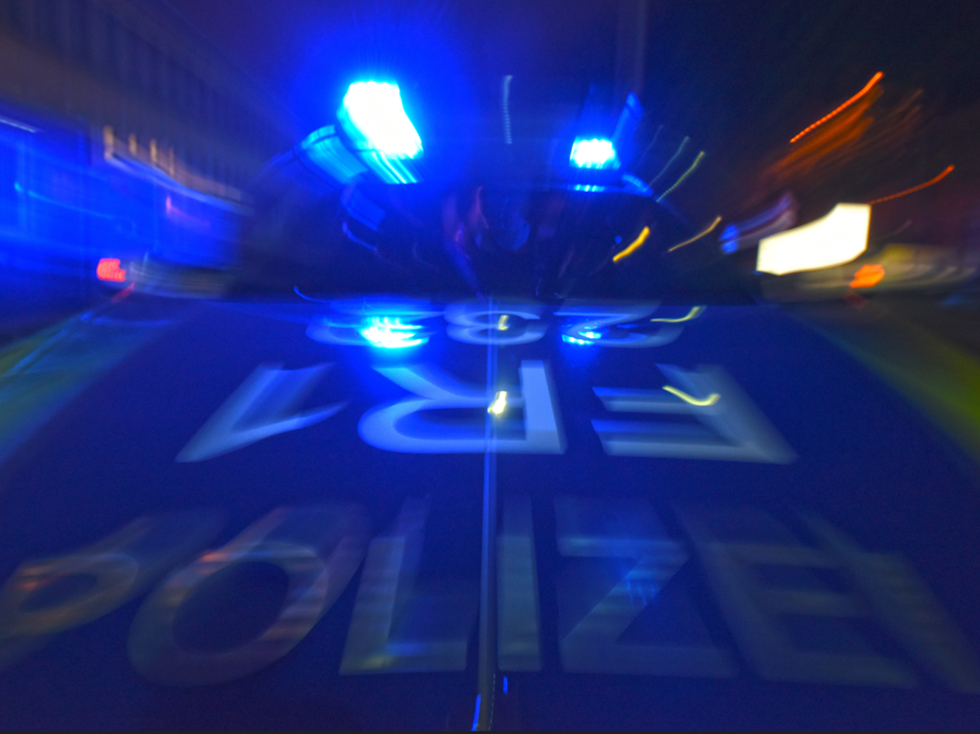 Ein Polizeifahrzeug steht mit Blaulicht auf der Straße.