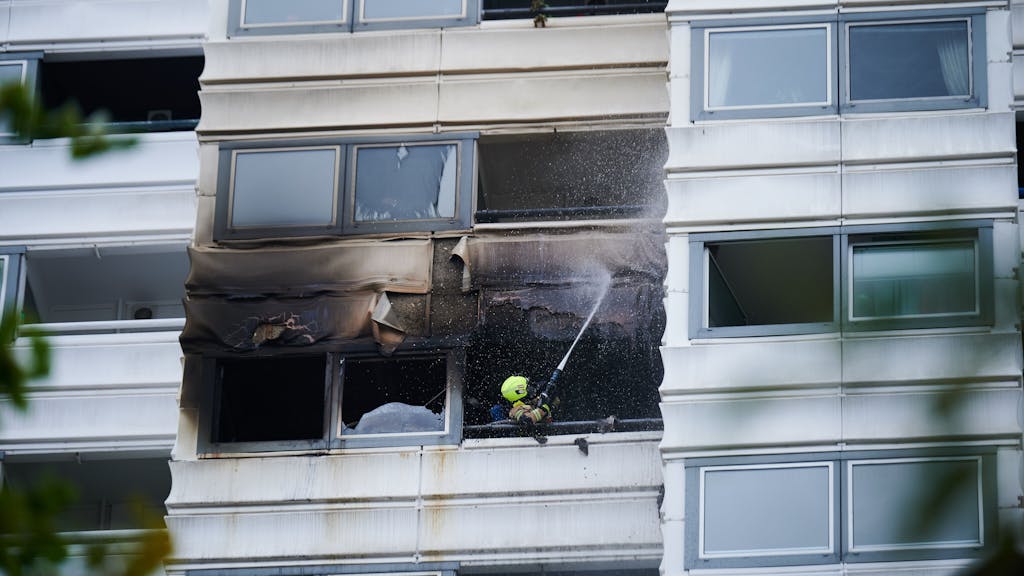 Ein Feuerwehrmann löscht einen Brand in einem Hochhaus. Wegen eines Brandes im zehnten Stock eines Hochhauses in Berlin sind zwei Menschen aus dem Gebäude gesprungen und ums Leben gekommen.