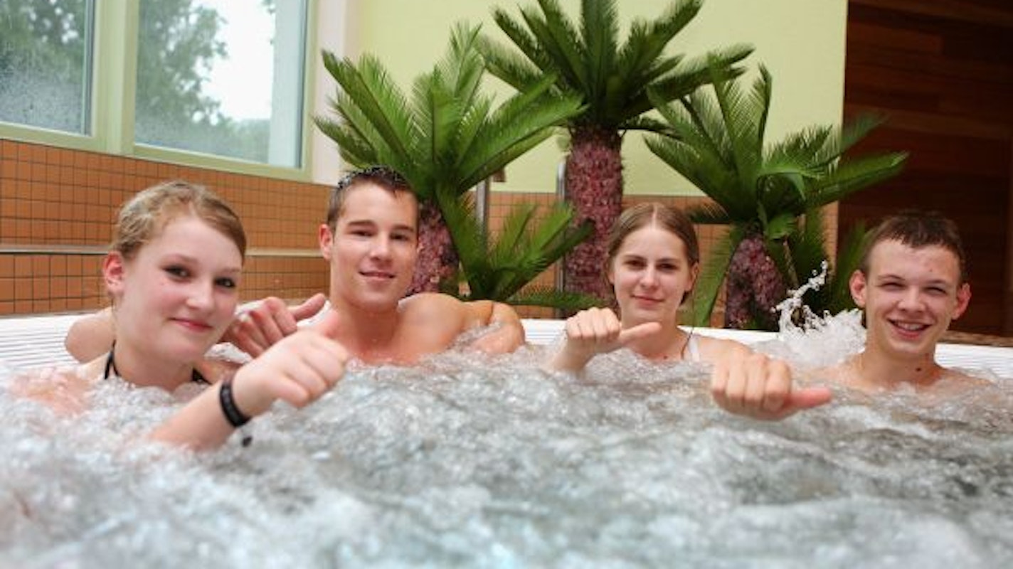 Vier Jugendliche sitzen in einem Whirlpool des Hallenbads Badino in Overath.