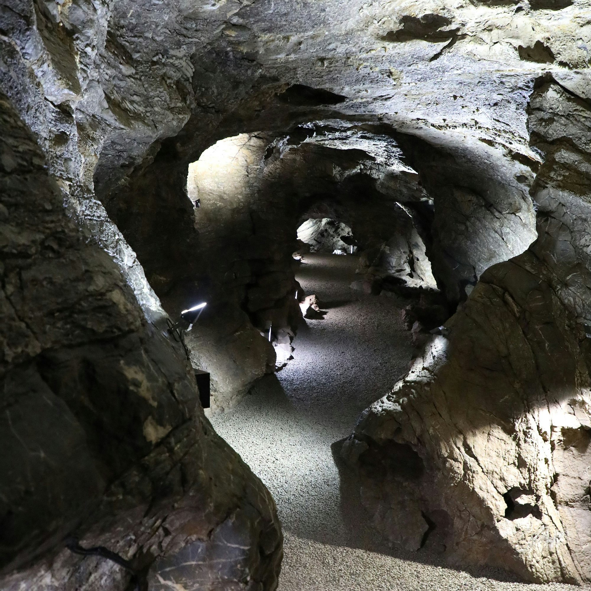 Ein Gang der Aggertalhöhle ist geheimnisvoll mit Licht ausgeleuchtet.