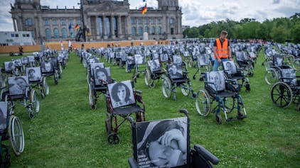 Aktion der Aktion „Nichtgenesen“ Anfang Juli vor dem Reichstag in Berlin. Auf den Rollstühlen stehen Bilder  mit Namen von Long Covid, ME/CFS und Post Vac- Betroffenen.