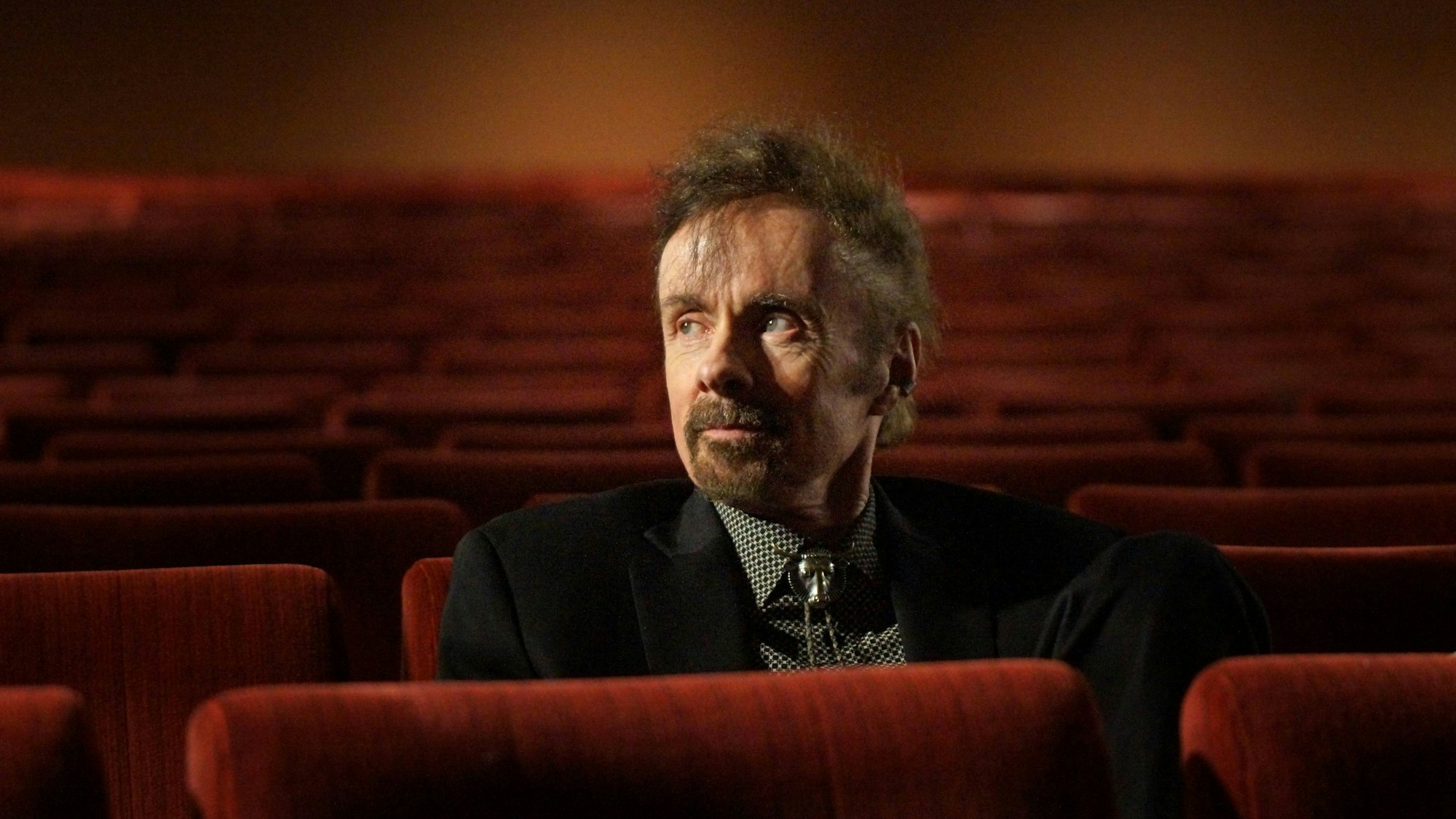 T. C. Boyle sitzt in einem Kinosaal mit roten Sesseln.