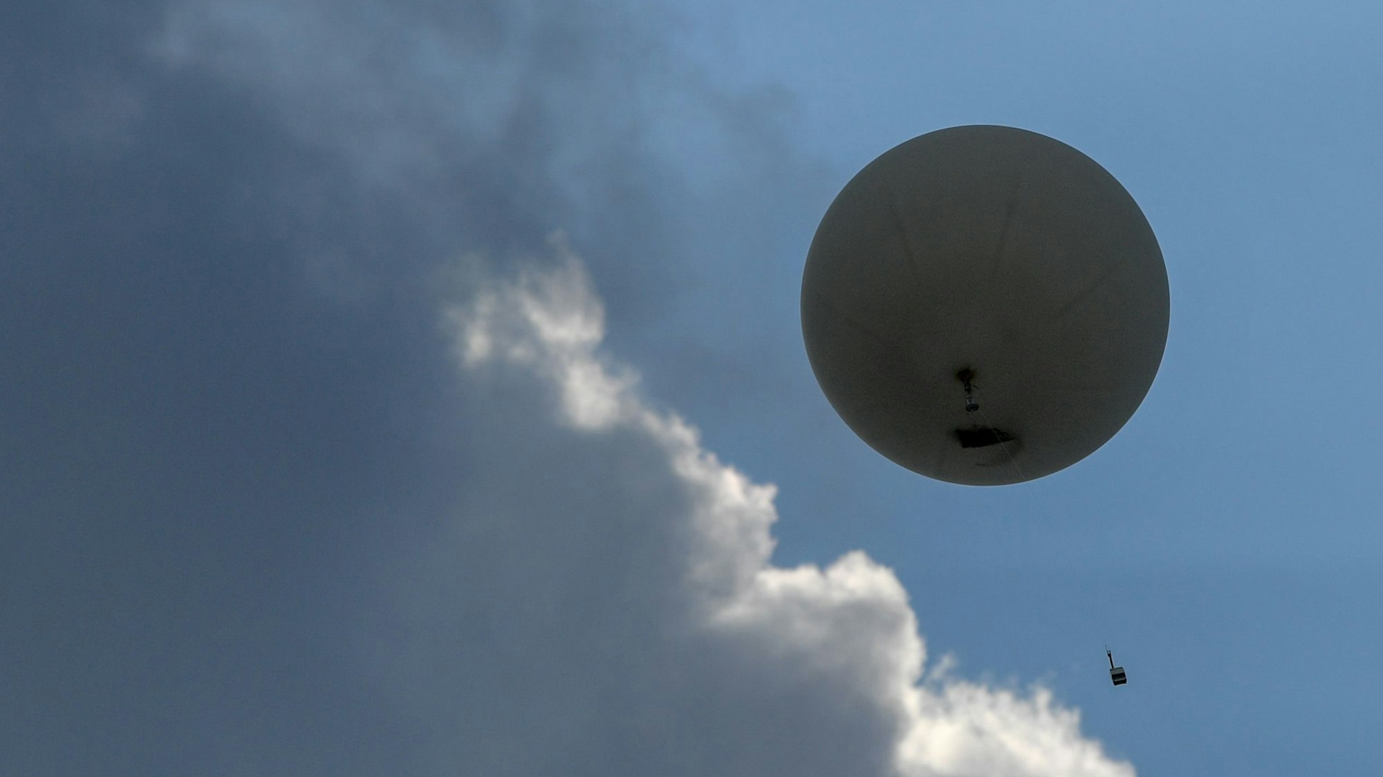 Ein Wetterballon mit einer Radiosonde steigt in den Himmel, der mit Wolken bedeckt ist. (Symbolbild)