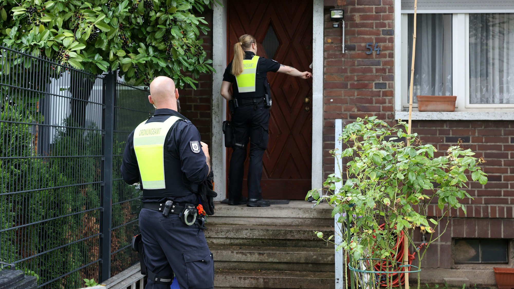 Zwei Einsatzkräfte des Ordnungssamtes klingeln an einer Haustür bei einer Evakuierung nach einem Bombenfund in Köln.