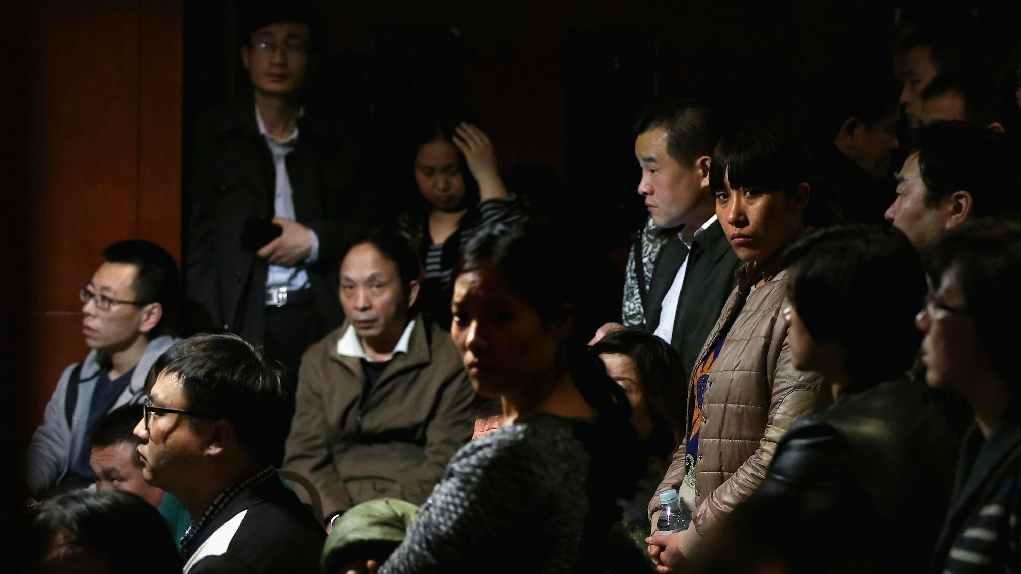 Chinesische Angehörige der vermissten Passagiere an Bord des Malaysia Airlines Fluges MH370 schauen auf einen Fernseher, der eine malaysische Pressekonferenz zeigt.