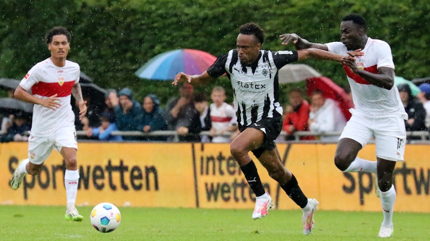 Nathan Ngoumou von Borussia Mönchengladbach (M.) im Testspiel am 29. Juli 2023 im Zweikampf mit Silas vom VfB Stuttgart (r.).